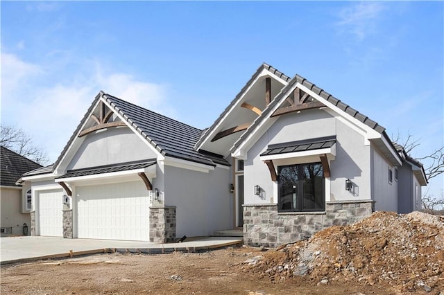 view of front of home with metal roof, a garage, stone siding, concrete driveway, and a standing seam roof