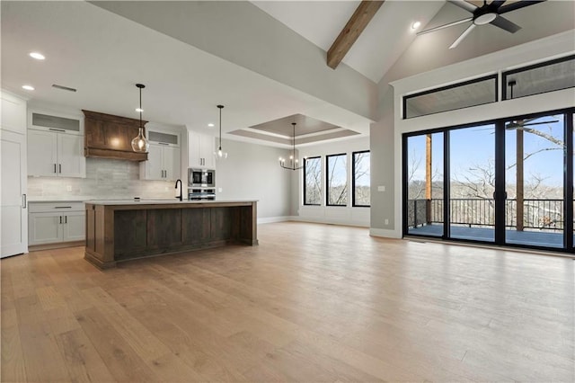 kitchen featuring open floor plan, light countertops, appliances with stainless steel finishes, light wood-type flooring, and backsplash