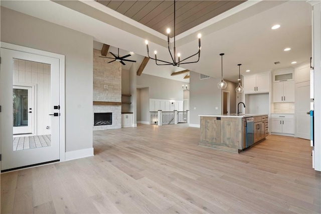 kitchen with ceiling fan, white cabinetry, open floor plan, light wood finished floors, and pendant lighting