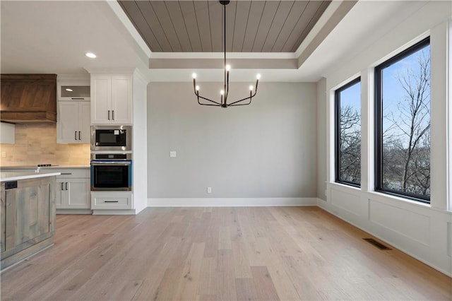 kitchen with visible vents, a tray ceiling, stainless steel appliances, light countertops, and backsplash