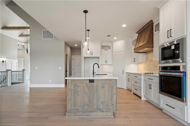 kitchen with oven, visible vents, custom exhaust hood, built in microwave, and tasteful backsplash