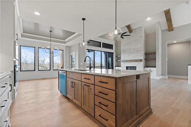 kitchen with ceiling fan with notable chandelier, a sink, dishwasher, light wood finished floors, and a raised ceiling