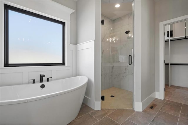 full bath featuring a stall shower, baseboards, and a freestanding tub