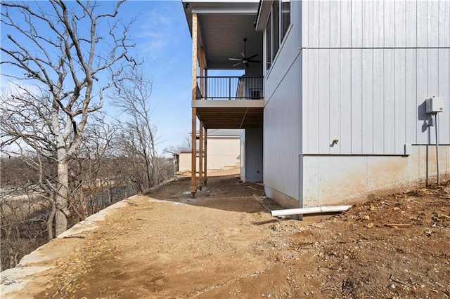 view of side of property featuring a ceiling fan, a balcony, and a carport