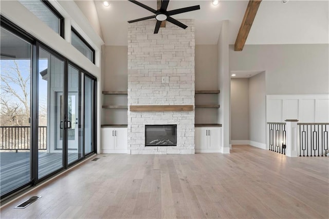 115 Teton Rdg, Lake Winnebago, MO 64034 - unfurnished living room with ceiling fan, high vaulted ceiling, wood finished floors, beamed ceiling, and a stone fireplace