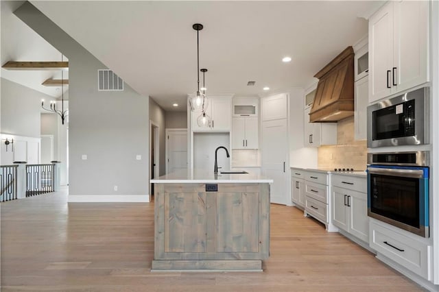 115 Teton Rdg, Lake Winnebago, MO 64034 - kitchen featuring stainless steel appliances, light wood-type flooring, backsplash, premium range hood, and light countertops