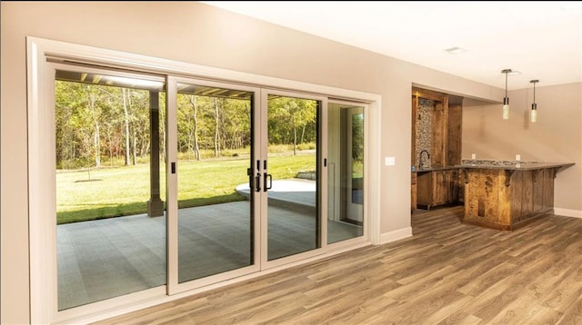 doorway to outside featuring baseboards and wood finished floors