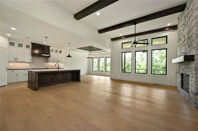 119 Teton Rdg, Lake Winnebago, MO 64034 - kitchen with open floor plan, backsplash, a stone fireplace, light wood-style flooring, and beam ceiling