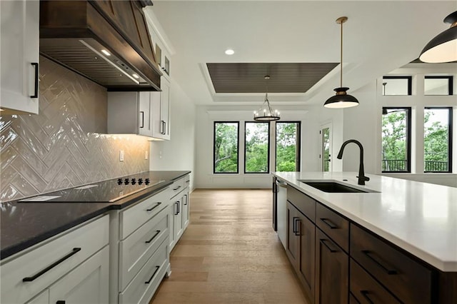 119 Teton Rdg, Lake Winnebago, MO 64034 - kitchen with custom exhaust hood, black electric cooktop, a tray ceiling, tasteful backsplash, and light wood finished floors