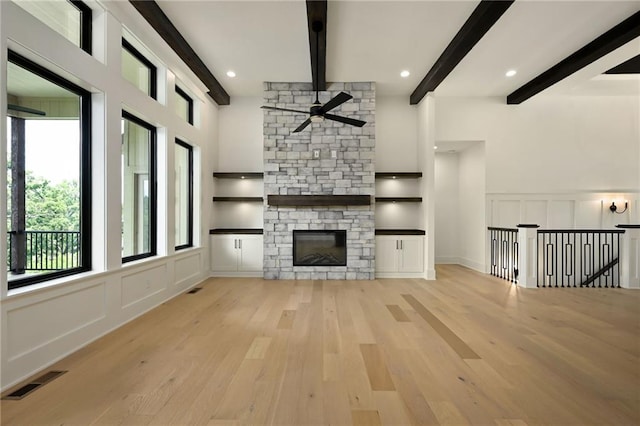 119 Teton Rdg, Lake Winnebago, MO 64034 - unfurnished living room with a ceiling fan, a decorative wall, wood finished floors, beamed ceiling, and a fireplace