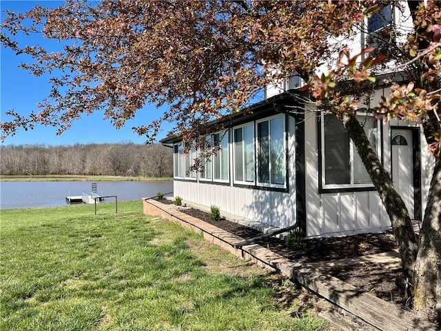 view of home's exterior with a water view and a yard