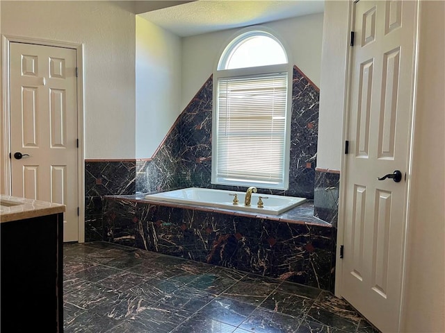 bathroom with tiled bath, vanity, and tile floors