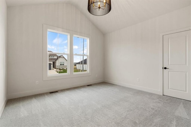 unfurnished room with carpet floors, a notable chandelier, and vaulted ceiling