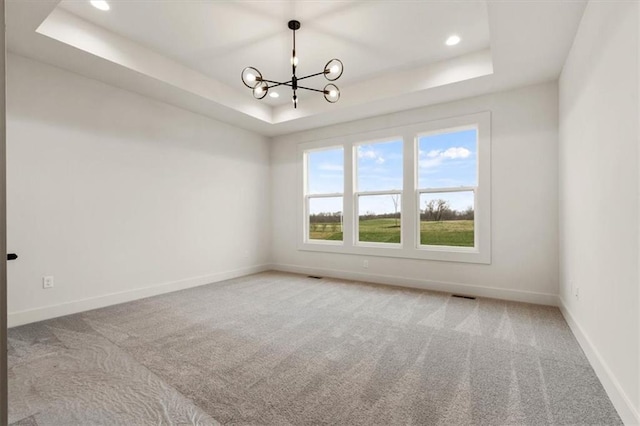 unfurnished room featuring a chandelier, carpet, and a tray ceiling