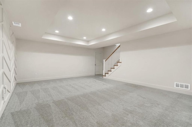 carpeted empty room with a tray ceiling