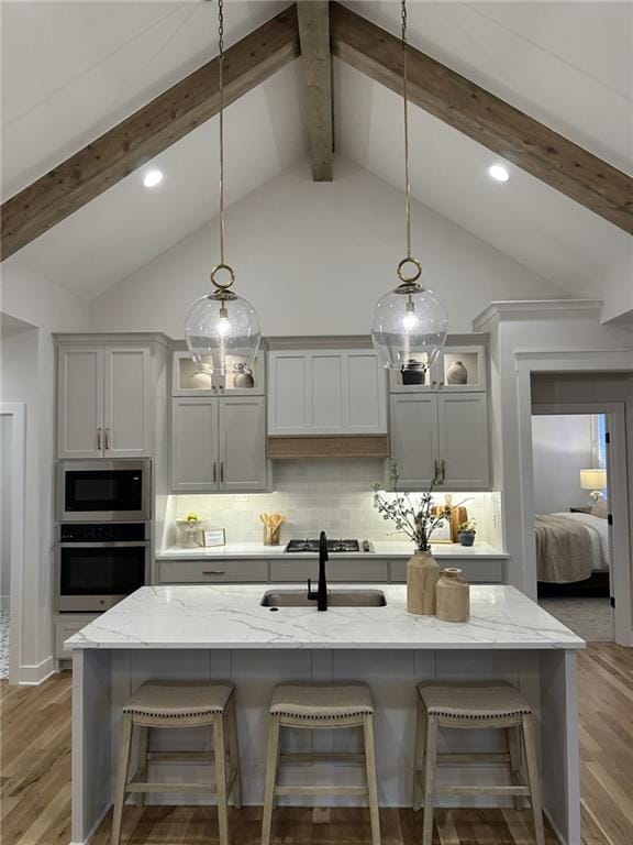 20132 Barker St, Spring Hill, KS 66083 - kitchen with stainless steel appliances, beam ceiling, light wood-type flooring, light stone counters, and a breakfast bar