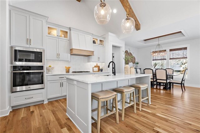 20132 Barker St, Spring Hill, KS 66083 - kitchen with appliances with stainless steel finishes, tasteful backsplash, custom range hood, a kitchen breakfast bar, and light wood-style flooring