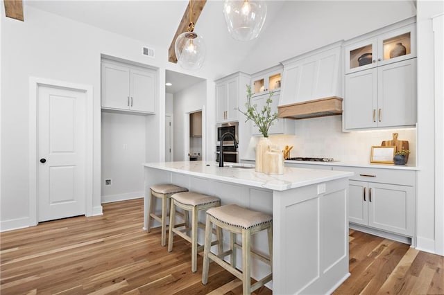 20132 Barker St, Spring Hill, KS 66083 - kitchen featuring light wood-style flooring, decorative backsplash, an island with sink, gas cooktop, and vaulted ceiling