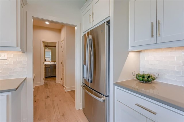 kitchen featuring tasteful backsplash, stainless steel fridge, light hardwood / wood-style floors, and white cabinets