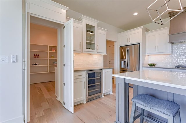 kitchen featuring wine cooler, a kitchen breakfast bar, and white cabinets