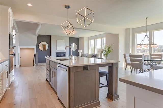 kitchen featuring white cabinetry, a large fireplace, sink, and an island with sink