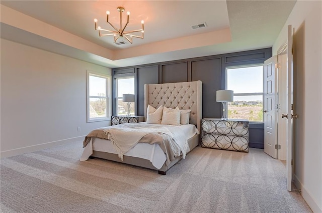 carpeted bedroom with a chandelier and a raised ceiling