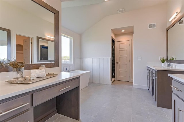 bathroom featuring tile patterned flooring, double vanity, vaulted ceiling, and a bath