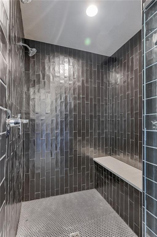 bathroom with tiled shower and tile walls