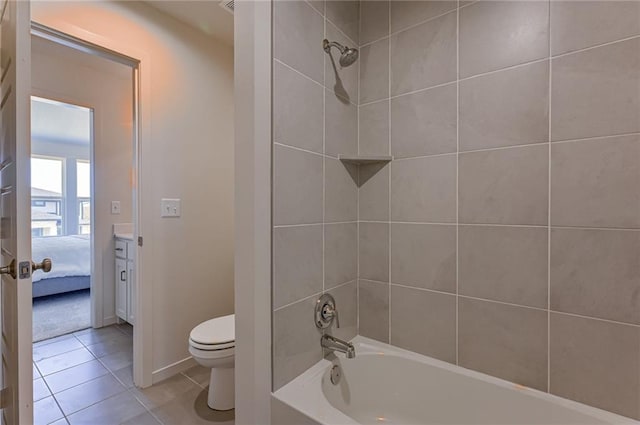 bathroom with tile patterned flooring, tiled shower / bath combo, and toilet