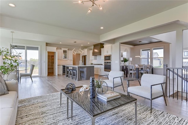 living room with an inviting chandelier, a wealth of natural light, and light wood-type flooring