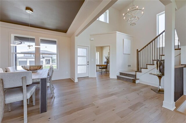 dining space featuring a towering ceiling, a notable chandelier, and light hardwood / wood-style flooring