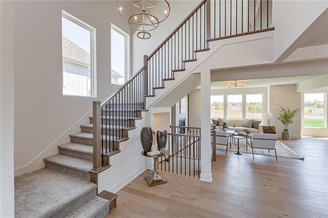 stairway with hardwood / wood-style flooring, a chandelier, and a high ceiling