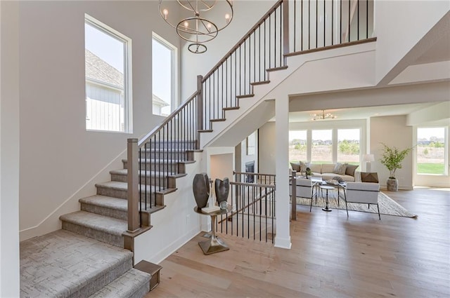 staircase featuring hardwood / wood-style flooring, an inviting chandelier, and a high ceiling