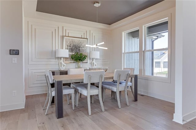 dining room featuring a tray ceiling and light wood-type flooring