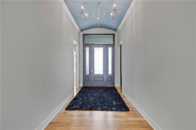 doorway to outside featuring hardwood / wood-style flooring, a notable chandelier, crown molding, and vaulted ceiling