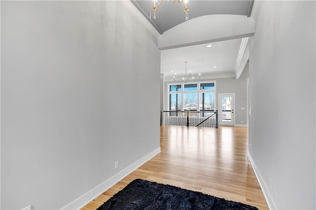 hall with light hardwood / wood-style floors, crown molding, and a notable chandelier