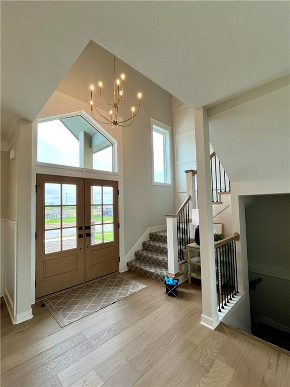 foyer entrance featuring a notable chandelier, french doors, and light wood-type flooring