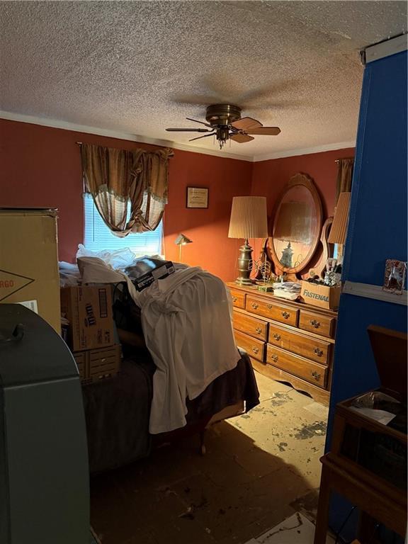 bedroom featuring a textured ceiling, ceiling fan, and ornamental molding