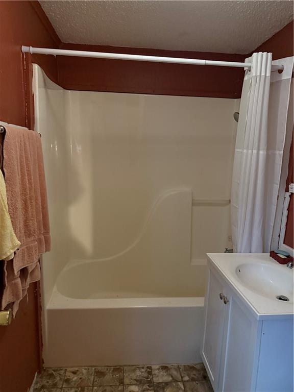 bathroom featuring shower / tub combo, vanity, and a textured ceiling