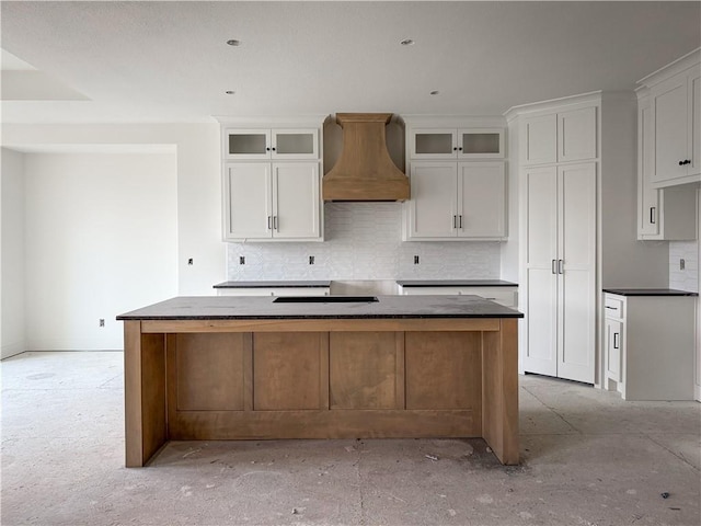 kitchen with backsplash, premium range hood, white cabinets, and a kitchen island