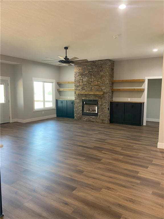 unfurnished living room featuring a fireplace, dark hardwood / wood-style floors, and ceiling fan