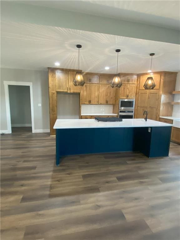 kitchen featuring a kitchen island with sink, hanging light fixtures, and dark hardwood / wood-style floors