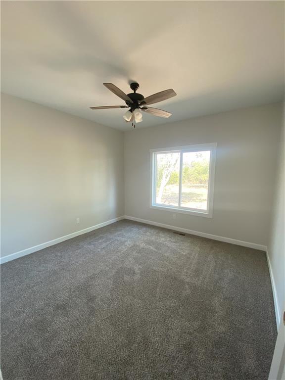 carpeted spare room with ceiling fan