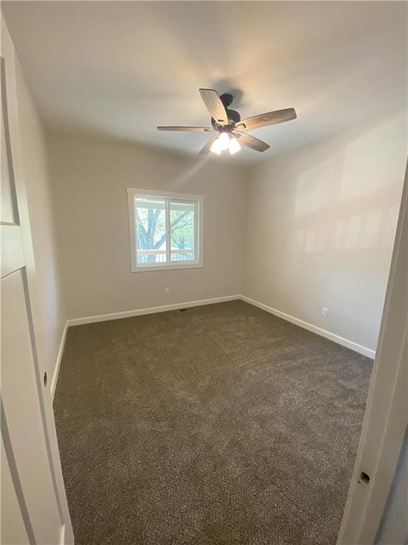 unfurnished room with dark carpet and ceiling fan