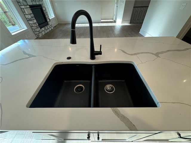 details featuring light stone countertops, a fireplace, a sink, and wood finished floors