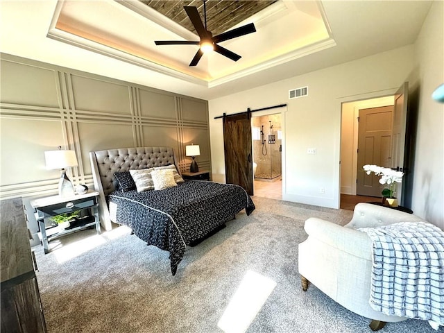 carpeted bedroom featuring a barn door, visible vents, a raised ceiling, a ceiling fan, and connected bathroom