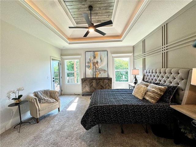 carpeted bedroom with a ceiling fan, access to outside, a raised ceiling, and multiple windows