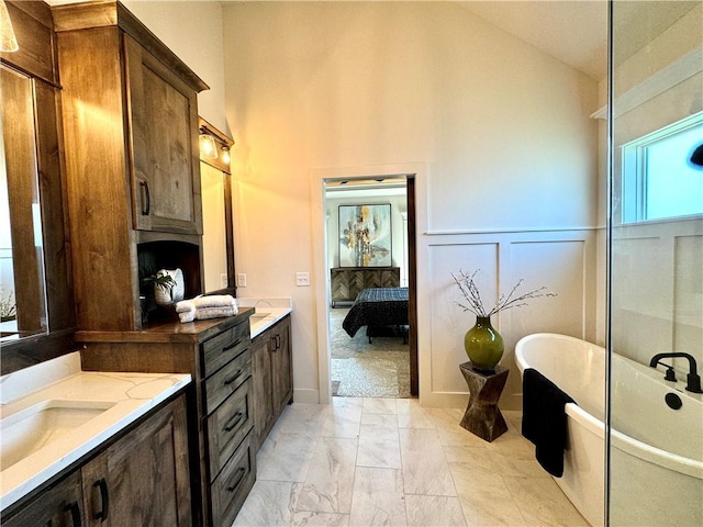 ensuite bathroom with ensuite bathroom, marble finish floor, a freestanding bath, vanity, and a decorative wall