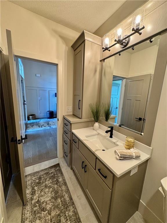 bathroom with toilet, a textured ceiling, and vanity