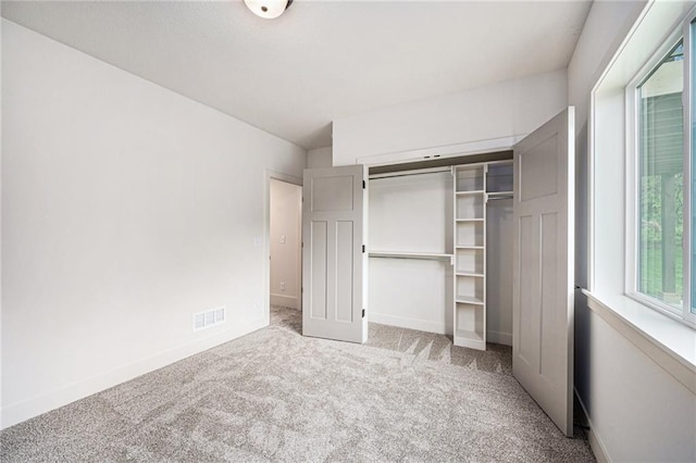 unfurnished bedroom featuring carpet floors, a closet, visible vents, and baseboards